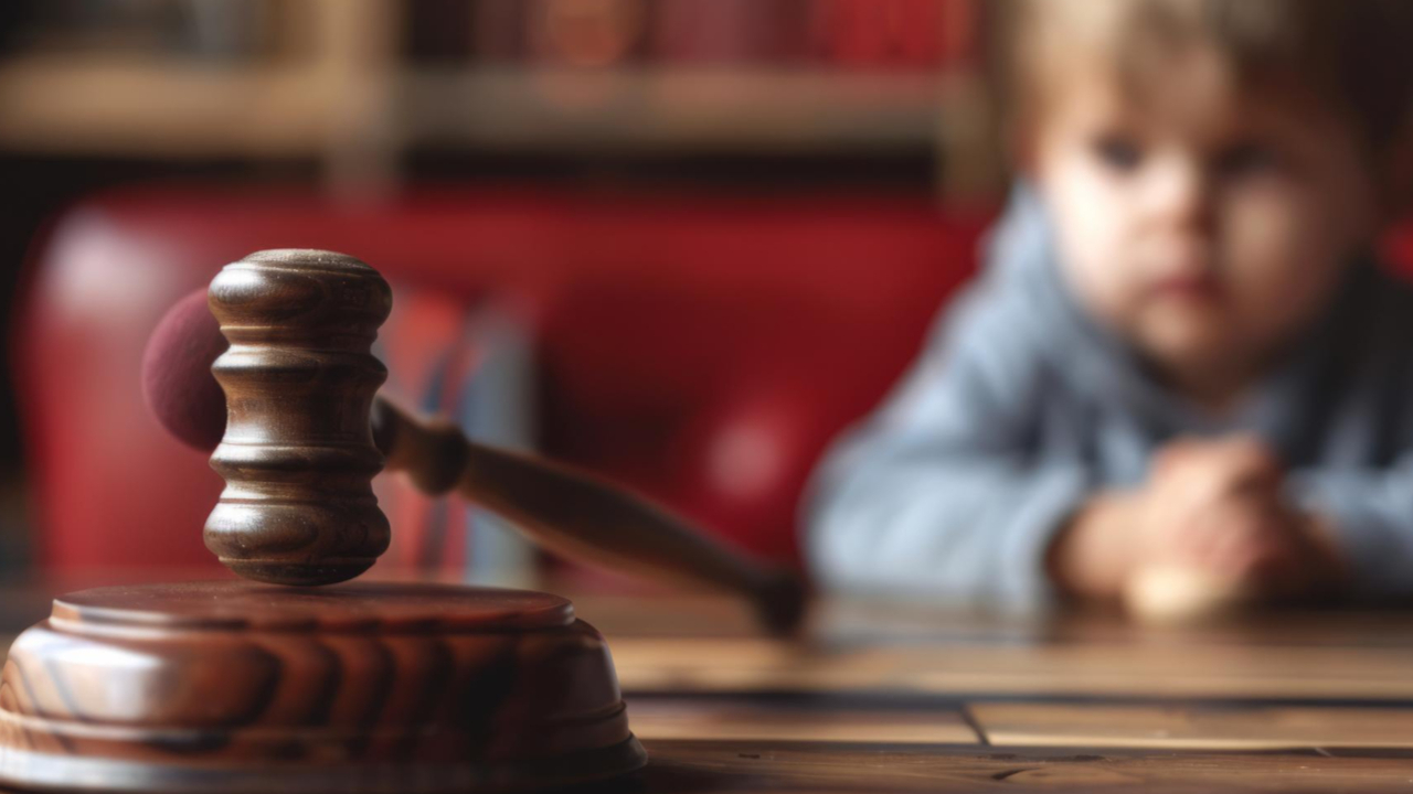 Criança desfocada ao fundo olhando o martelo do juiz legal aguardando o resultado do processo de pensão alimentícia